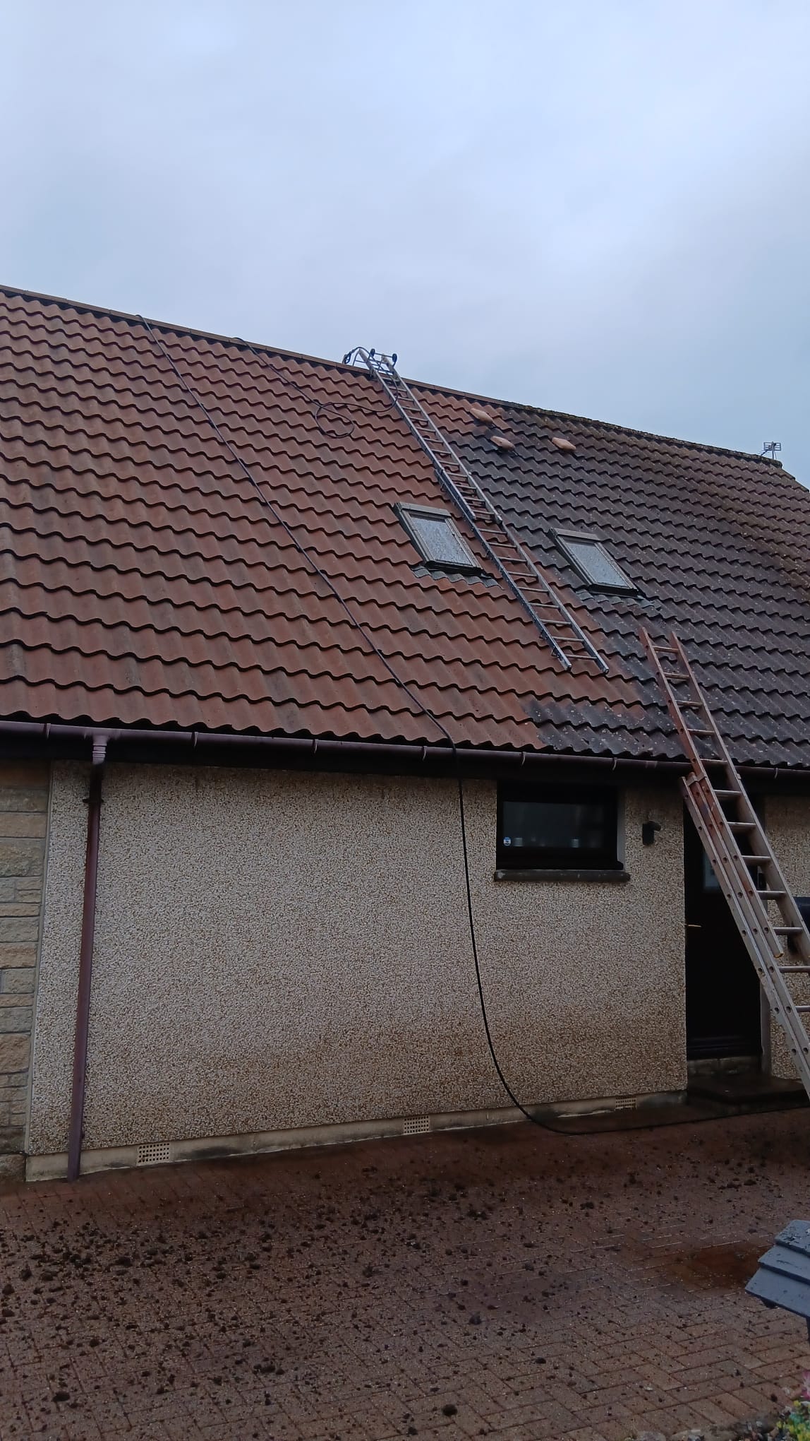 Roofer working at height with ladders on a tiled roof